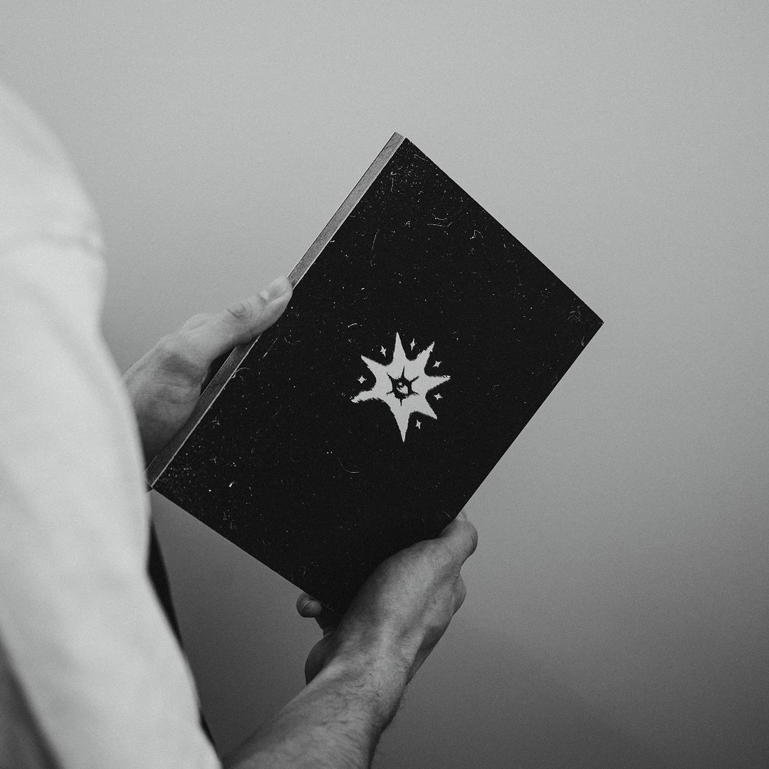 Livre noir avec logo tenu en diagonale sur fond clair