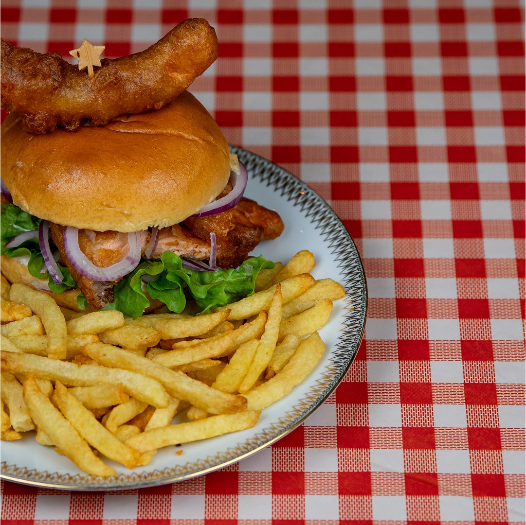 Assiette de burger poisson avec frites sur nappe à carreaux