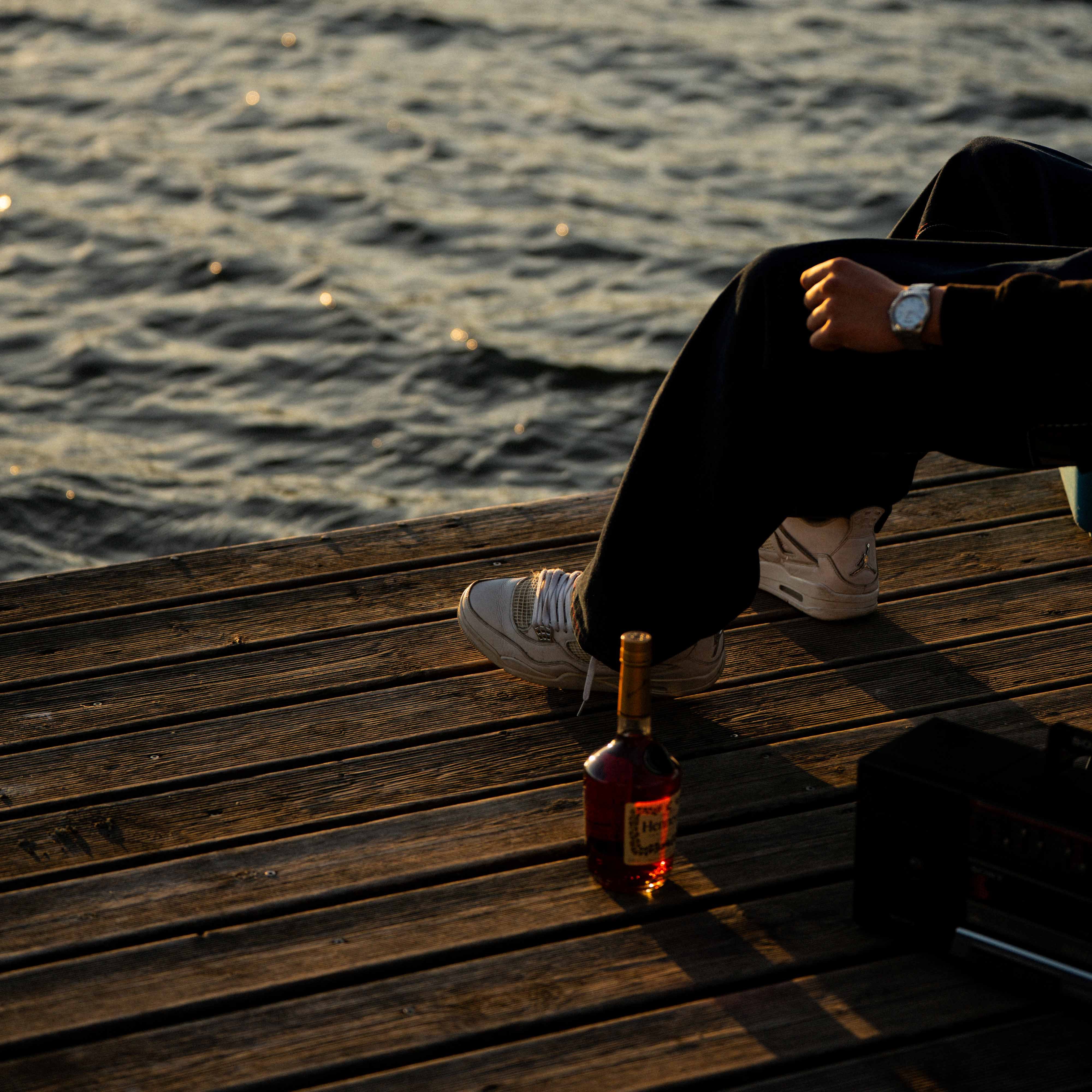 Rocka assis sur un quai avec une bouteille de whisky