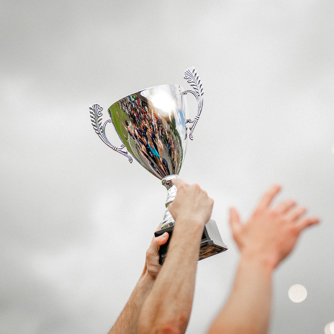 Mains tenant une coupe de football levée dans le ciel