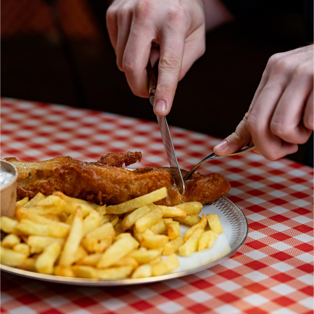 Main coupant du poisson avec couteau et fourchette
