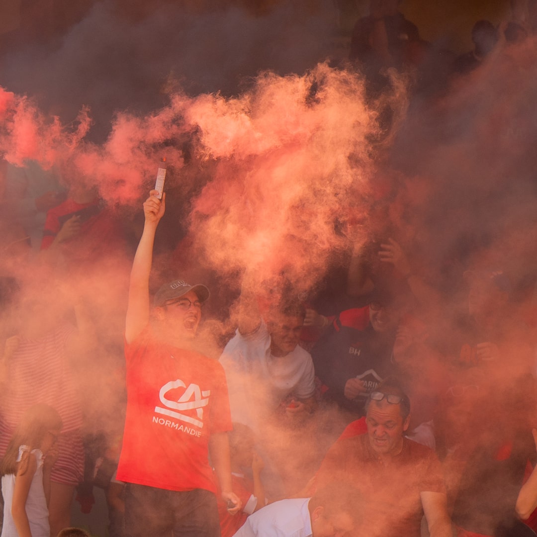Supporter avec fumigène rouge dans les tribunes