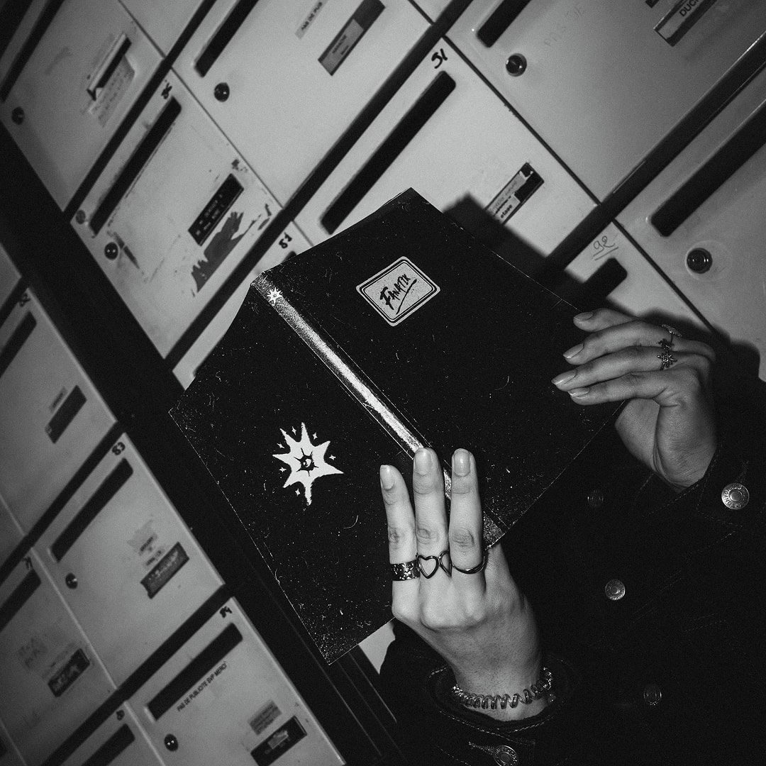 Main tenant un livre noir fermé avec logo, fond urbain flou
